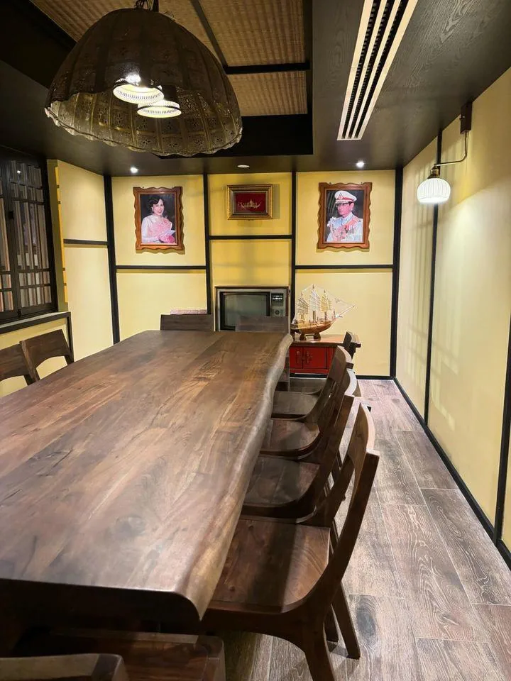 A private dining room with a long wooden table and royal portraits